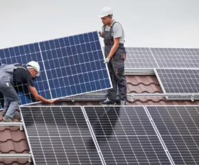 Men,Technicians,Carrying,Photovoltaic,Solar,Moduls,On,Roof,Of,House.